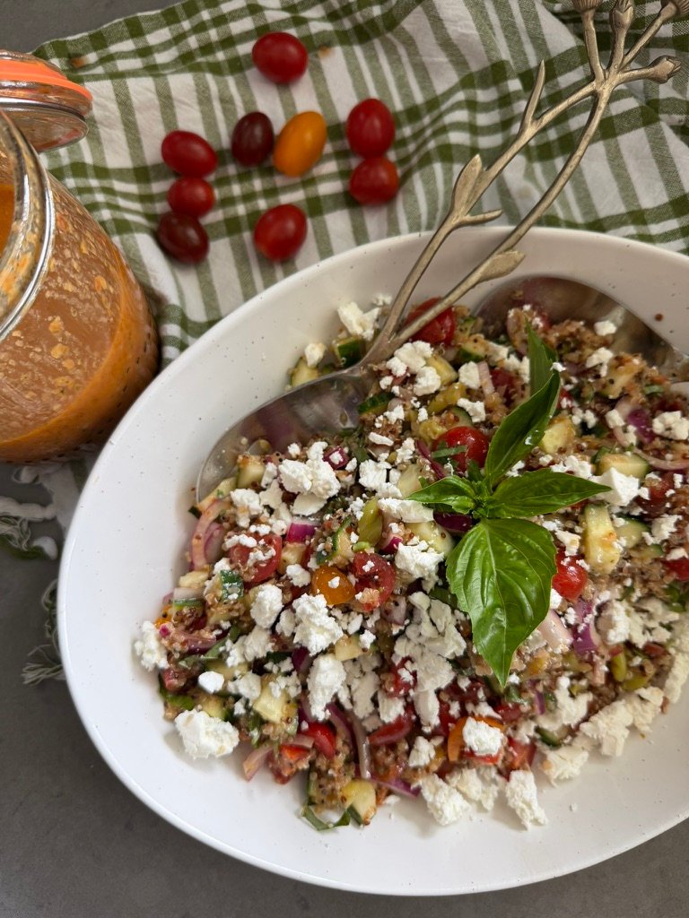 Mediterranean quinoa salad with sun dried tomato vinaigrette in a white bowl