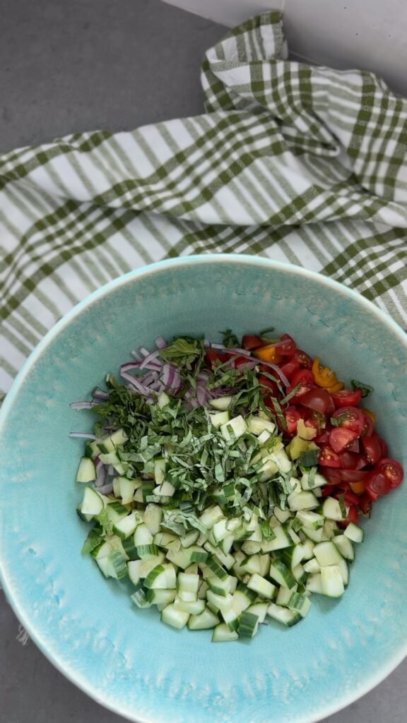 chopped cucumbers, tomatoes, onion, and basil in a bowl