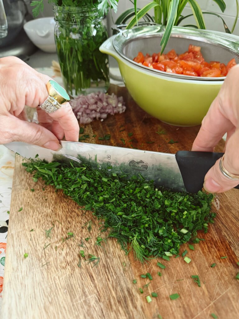 chef's knife chopping herbs on a cutting board