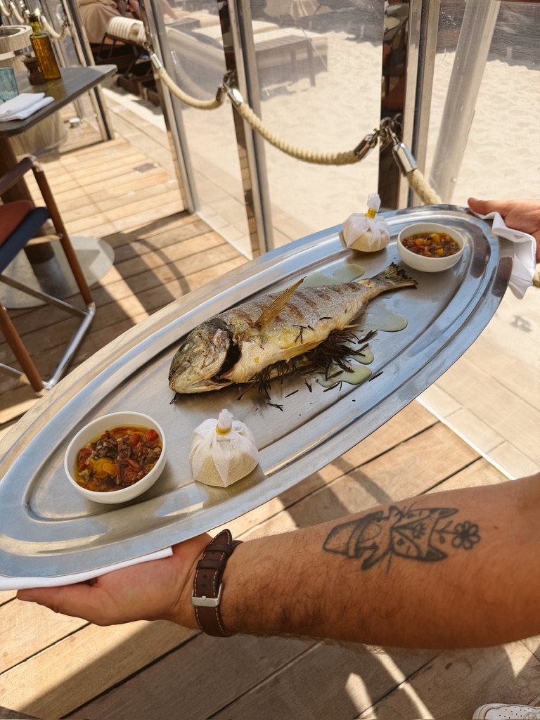 whole cooked fish on silver platter with vierge sauce