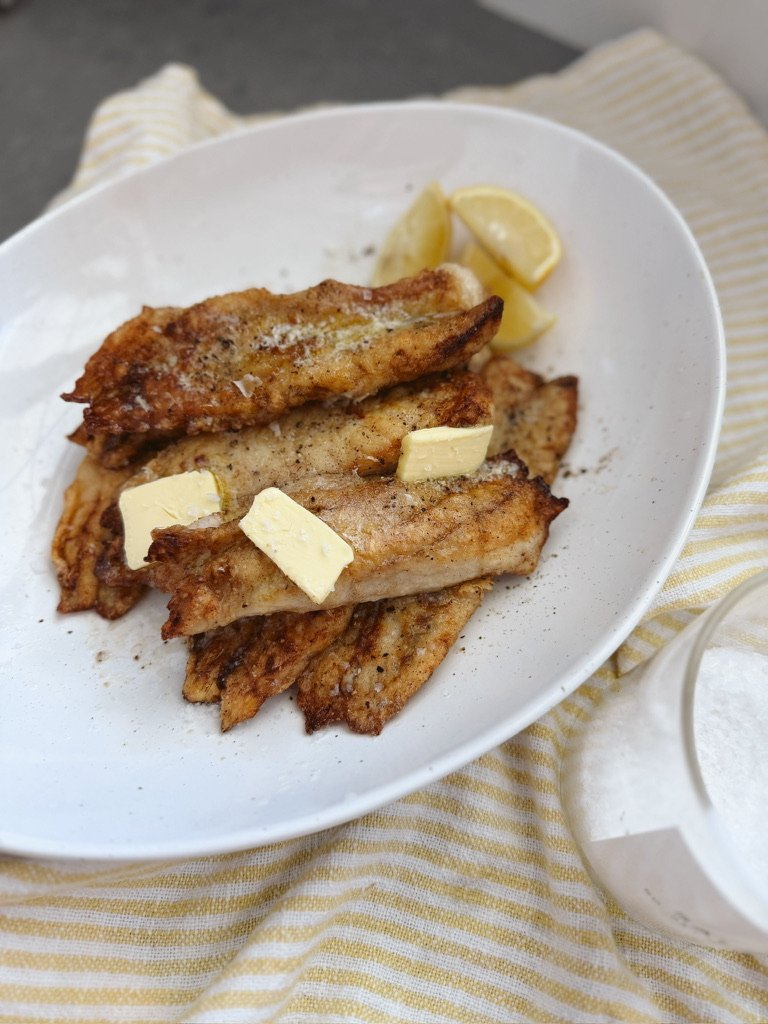 pan seared crispy fish fillet with butter on white plate