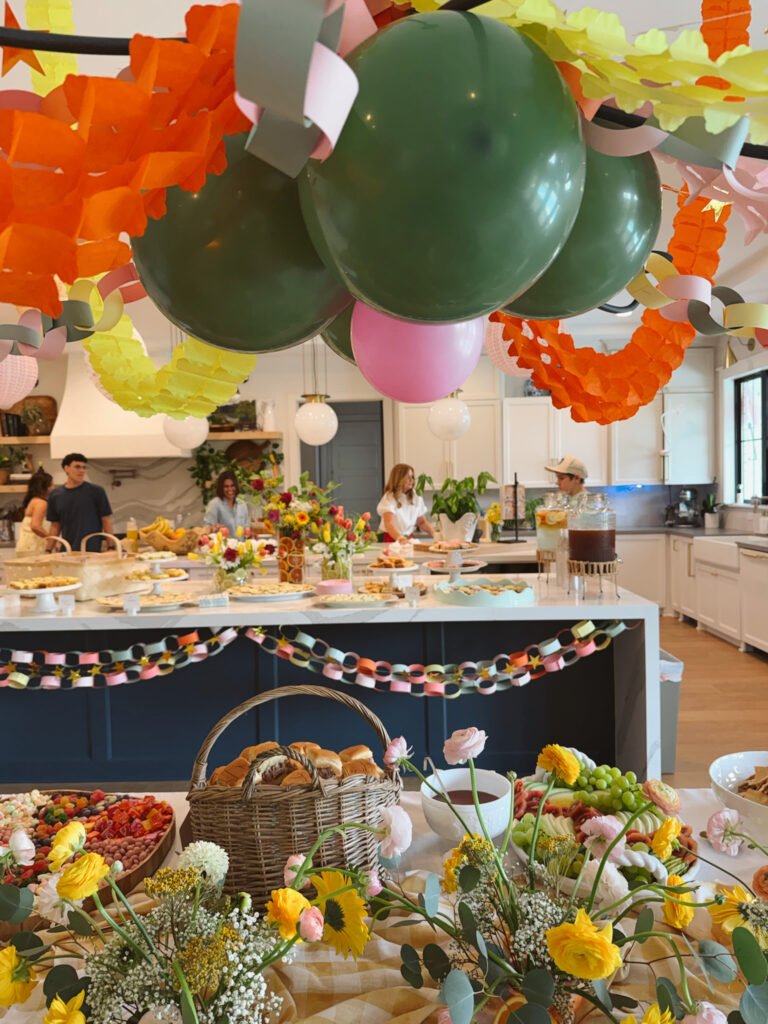 colorful party decorations food table with florals streamers and balloons