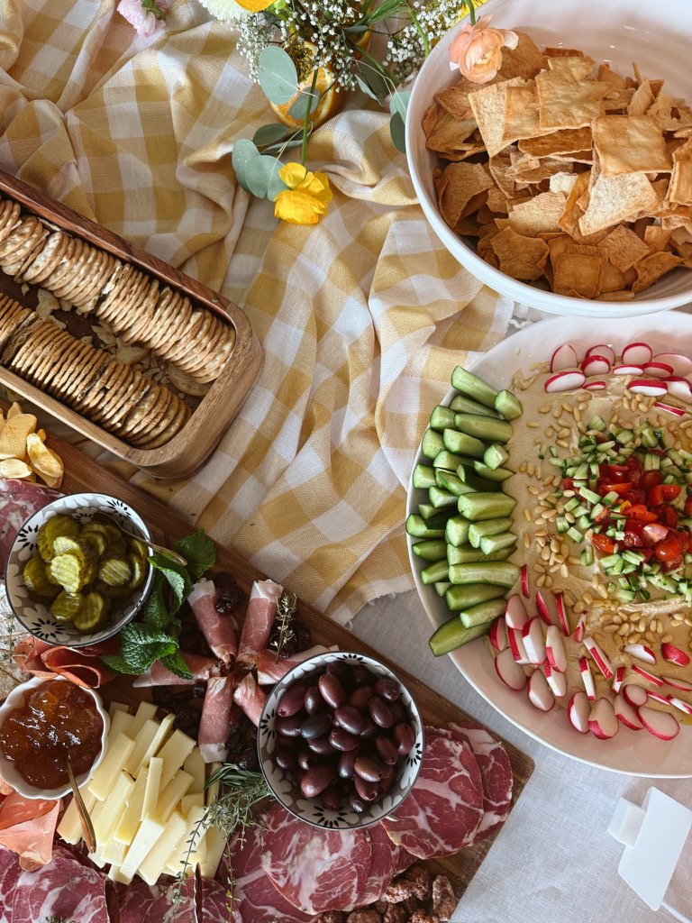 table of party food with bowl of hummus dips and crackers
