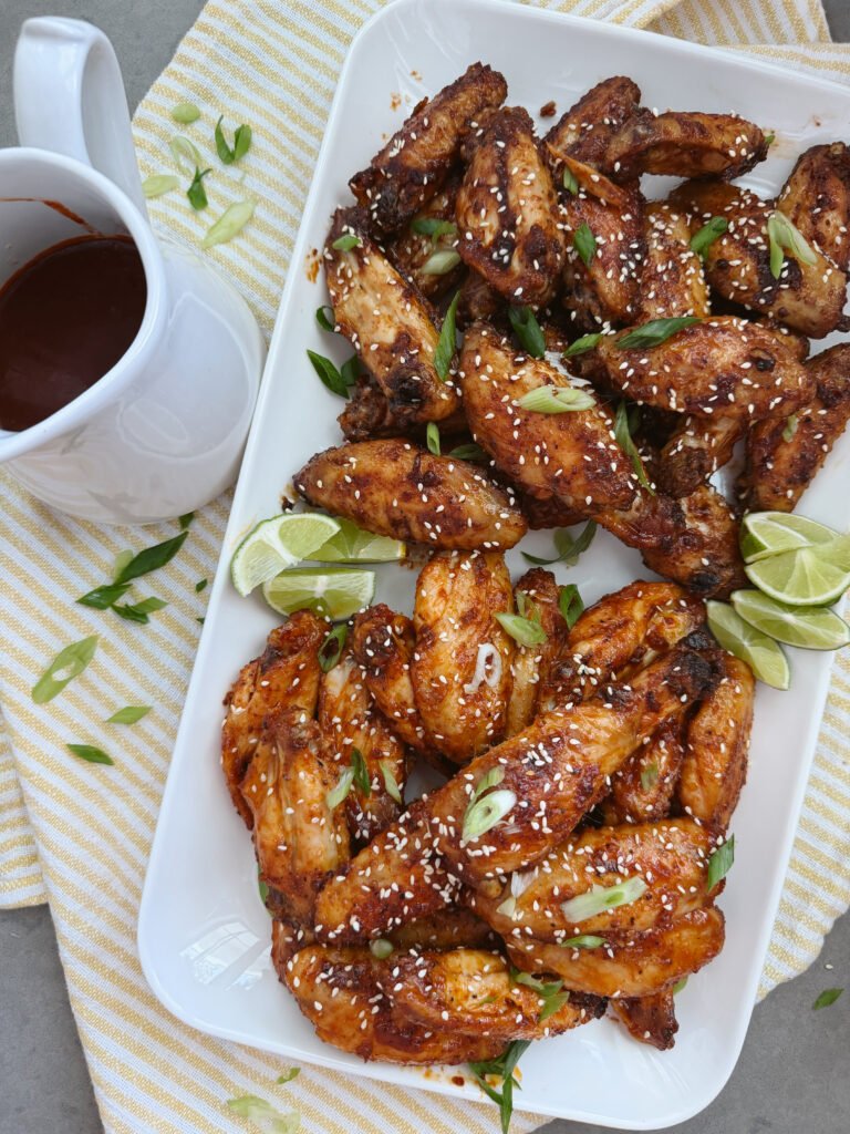sweet and spicy korean chicken wings with bowl of sauce and limes