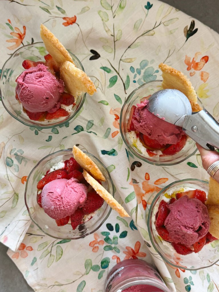 scooping sorbet on strawberries in glasses