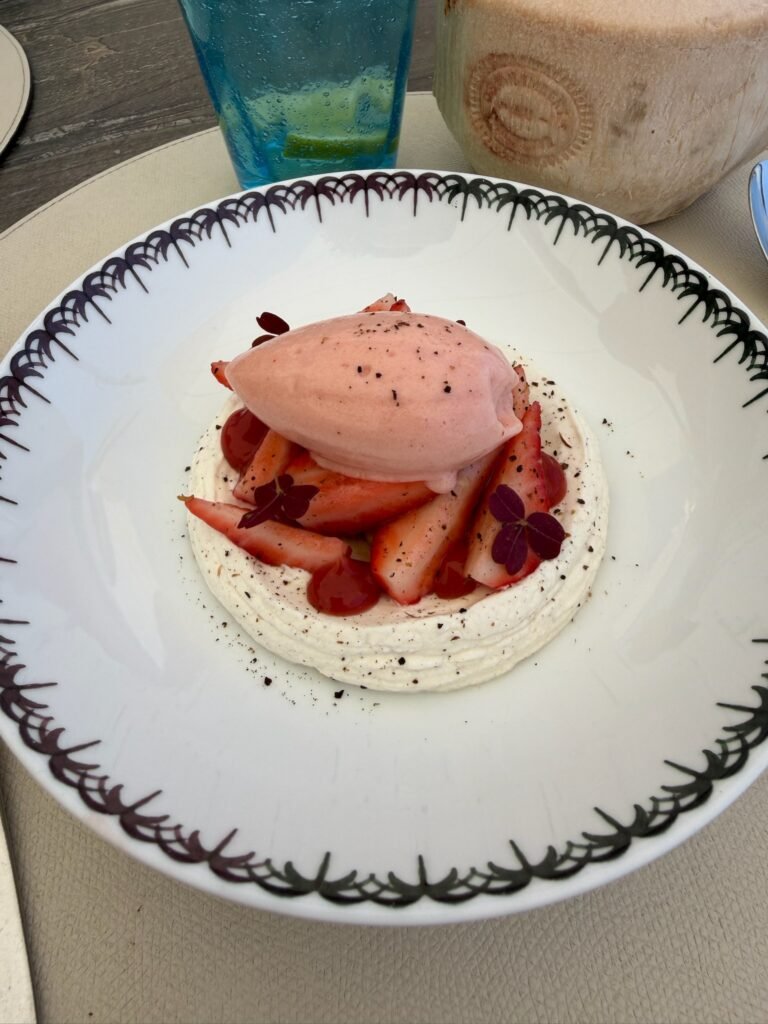 strawberry and cream dessert with raspberry sorbet and black pepper on white plate