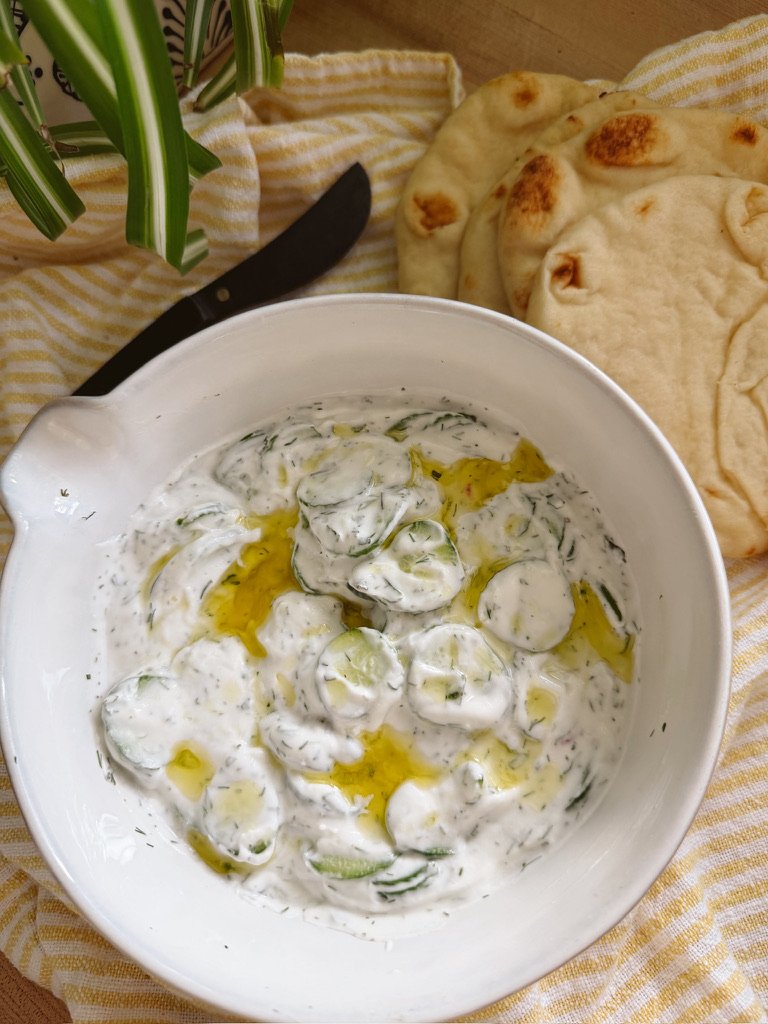 Easy Tzatziki sauce with sliced cucumbers in white bowl
